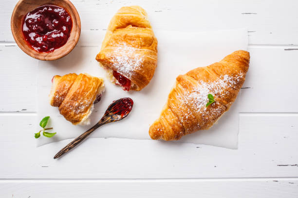 istock Croissants with berry jam on white wooden background. 1083411646