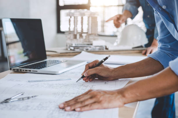 istock Hands of architect or engineer working on blueprint meeting for project working with partner on model building and engineering tools in working site, Construction concept 1083412236