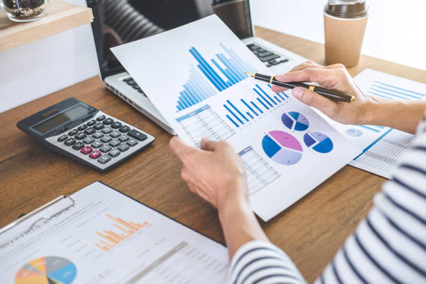 istock Female accountant calculations, audit and analyzing financial graph data with calculator and laptop Business, Financing, Accounting, Doing finance, Economy, Savings Banking Concept 1083412270