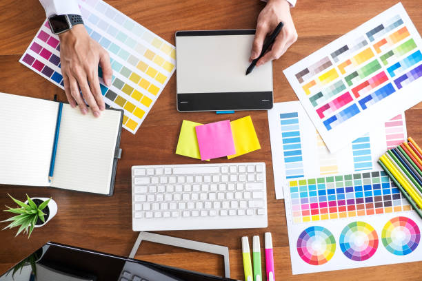 istock Image of male creative graphic designer working on color selection and drawing on graphics tablet at workplace with work tools and accessories, top view 1083412350