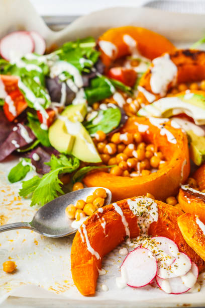 istock Baked pumpkin with chickpeas on a baking sheet with avocado, tahini and vegetables. 1083415012