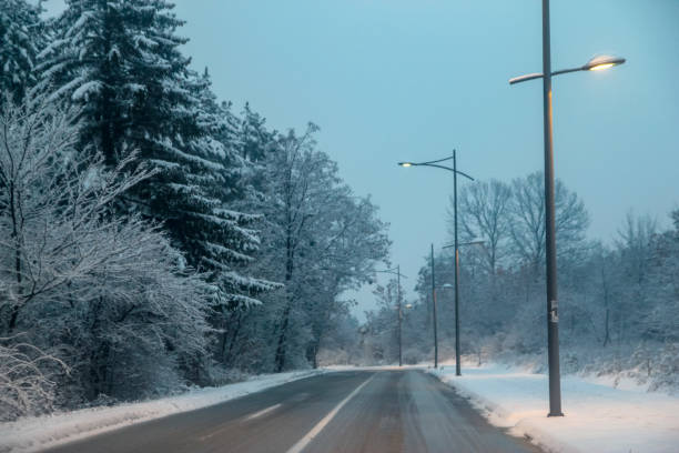 istock Snowy road at evening with road lights 1083418168
