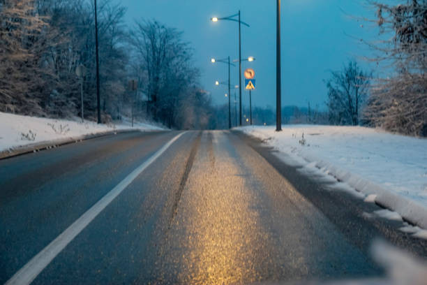 istock Snowy road at evening with road lights 1083418172
