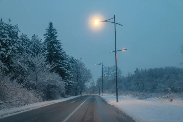 istock Snowy road at evening with road lights 1083418456
