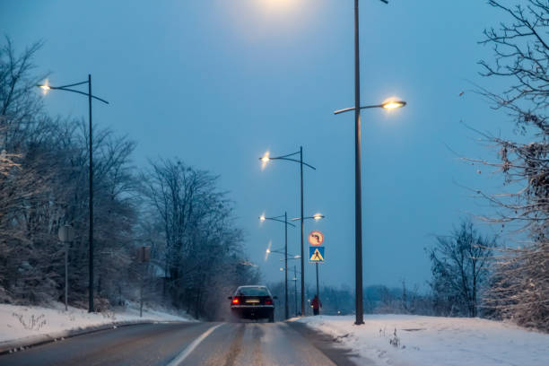 istock Snowy road at evening with road lights 1083419190
