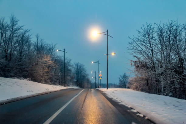 istock Snowy road at evening with road lights 1083419204