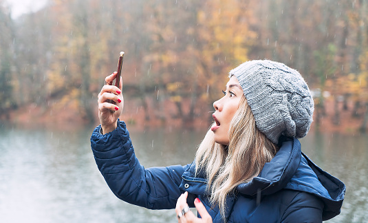 Asian woman searching for a mobile network in woods - No signal