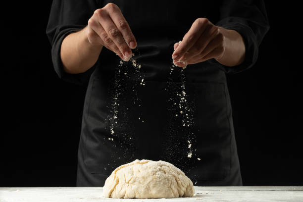 istock A chef in a black apron on a black background prepares Italian pizza, bread or pasta on a black background. Advertising, design for text, menu, recipe book. 1083443242