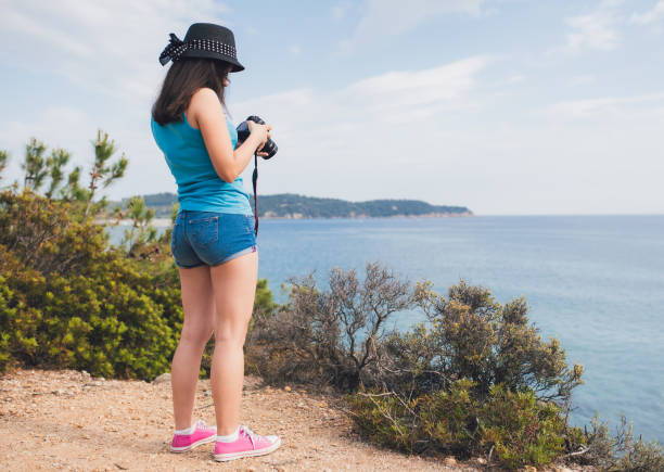 Young woman making photographs at a seaside viewpoint
