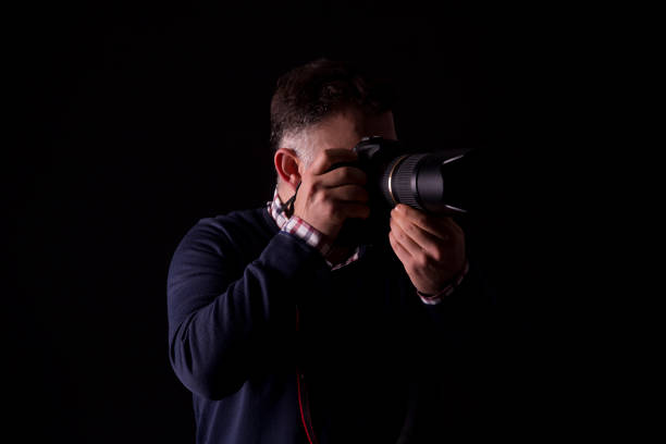 istock photographer taking photo black background 1083451118