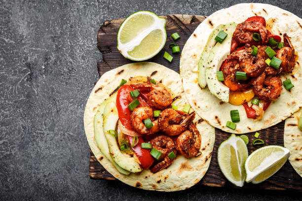 fajitas in tortillas con gamberi fritti, peperoni e cipolla serviti con avocado e cipolle verdi su tagliere in legno, vista dall'alto, sfondo del cibo con spazio per un testo - antipasto roasted pepper bell pepper pepper foto e immagini stock