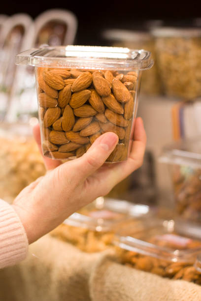 istock Female hand choosing almonds in the store 1083461434