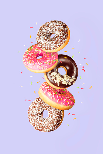 Sweet and colourful doughnuts falling or flying in motion on blue background. Mock up. Background concept.
