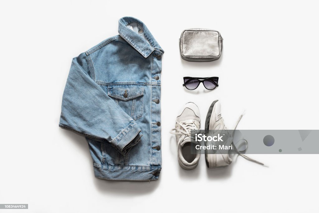 Casual fashion clothes and accessory set on white background. Jean jacket, sneakers, sunglasses, bag. Flat lay, top view. Clothing Stock Photo