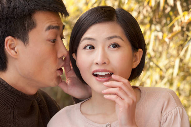 chinese man whispering to girlfriend - vacations women men stability imagens e fotografias de stock