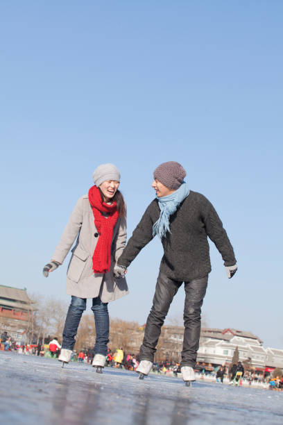 chinese couple ice skating - vacations women men stability imagens e fotografias de stock