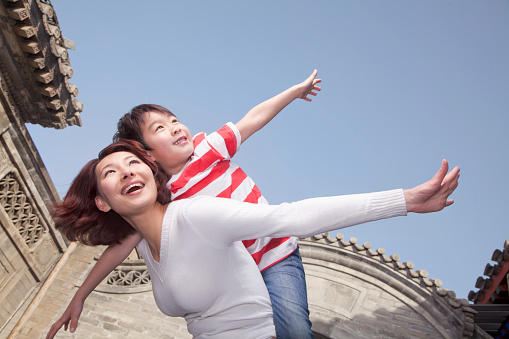 Chinese mother giving son piggyback ride