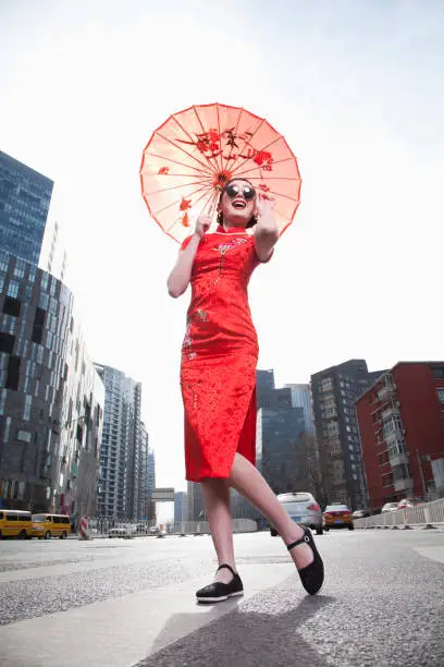 Photo of Glamorous Chinese woman in traditional clothing with parasol standing on the steet