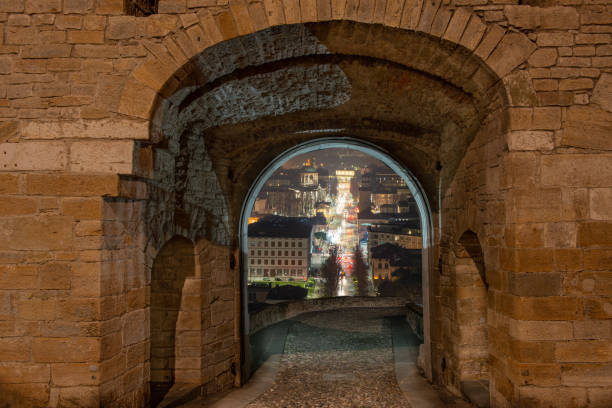 Porta San Giacomo illuminated at night with a view of lower Bergamo