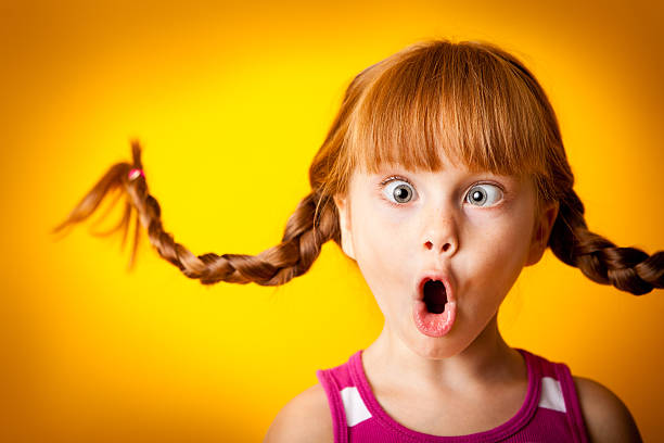 silly, red-haired girl with upward braids making crazy face - een gek gezicht trekken stockfoto's en -beelden