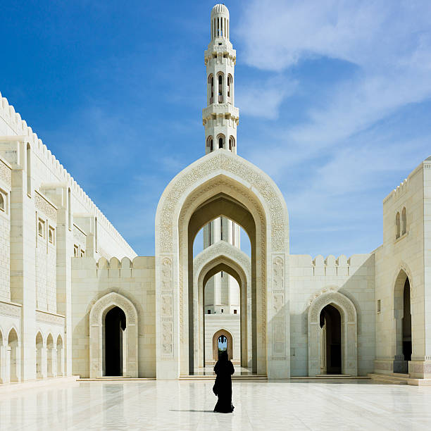 donna camminare all'interno della grande moschea del sultano qabus muscat, oman - oman greater masqat built structure mosque foto e immagini stock