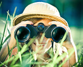 beautiful little explorer girl with binoculars at park