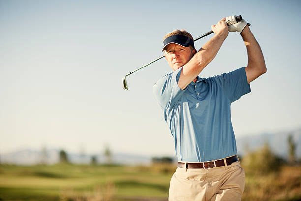 Golf Swing A middle-aged golfer swinging for the green. Just add type for the perfect golfing image. swinging stock pictures, royalty-free photos & images