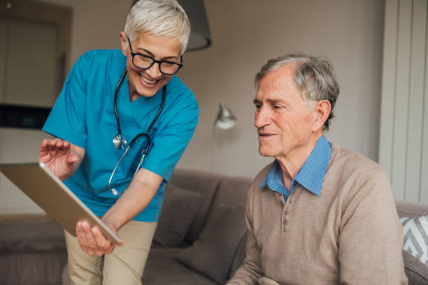 istock Senior man looking at digital tablet within a nurse 1083477222