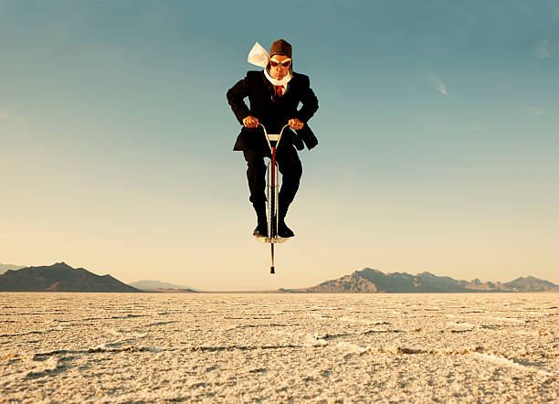 Businessman on Pogo Stick in Desert stock photo