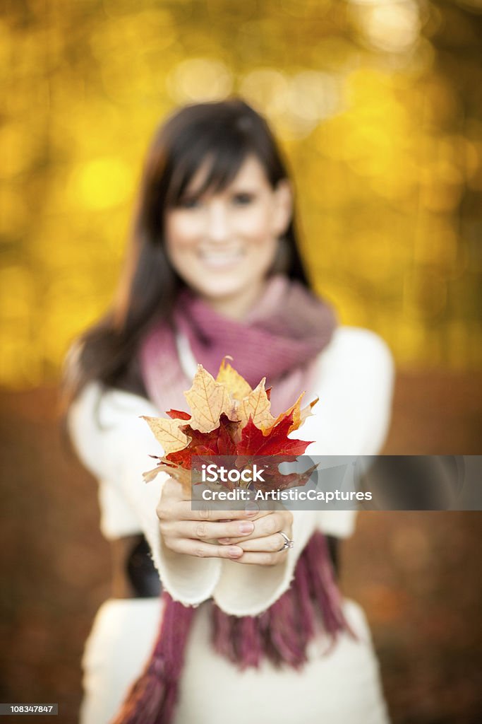 Счастливая молодая женщина держит вне в осень осень листья - Стоковые фото 25-29 лет роялти-фри