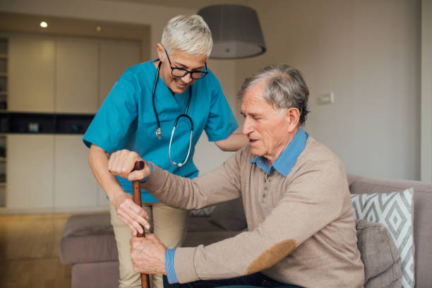 istock Female nurse helping patient to get up 1083478936