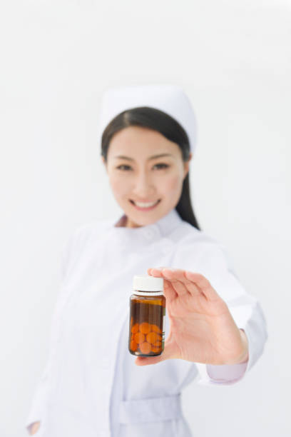 Wooden spoon with herbal pills capsules, dietary supplements vitamins on vegetables background