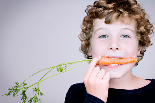 Pretty young woman eating carrot