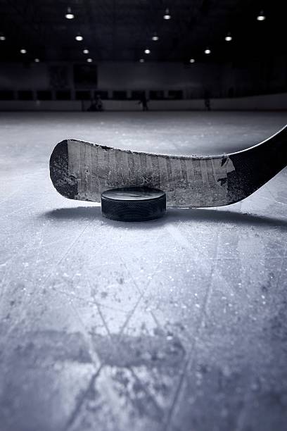 Hockey Stick and Puck A dramatic close up of a hockey stick and puck from a surface level view on the ice. There is ample space for copy. hockey puck photos stock pictures, royalty-free photos & images