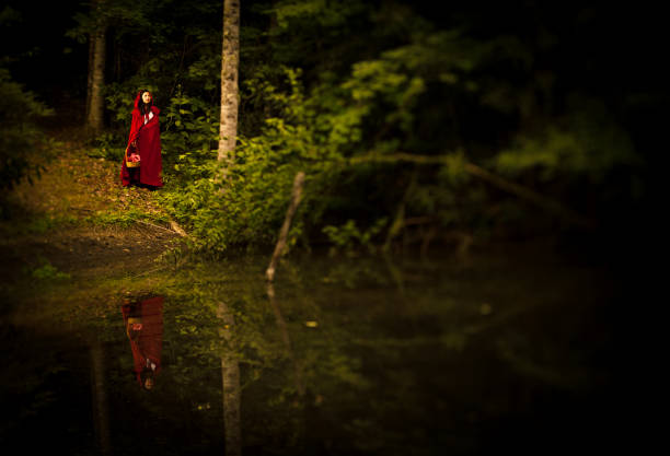 not so Little Red Riding Hood lost in the forest, standing in front of a small pond - shoot with a tilt shift lens