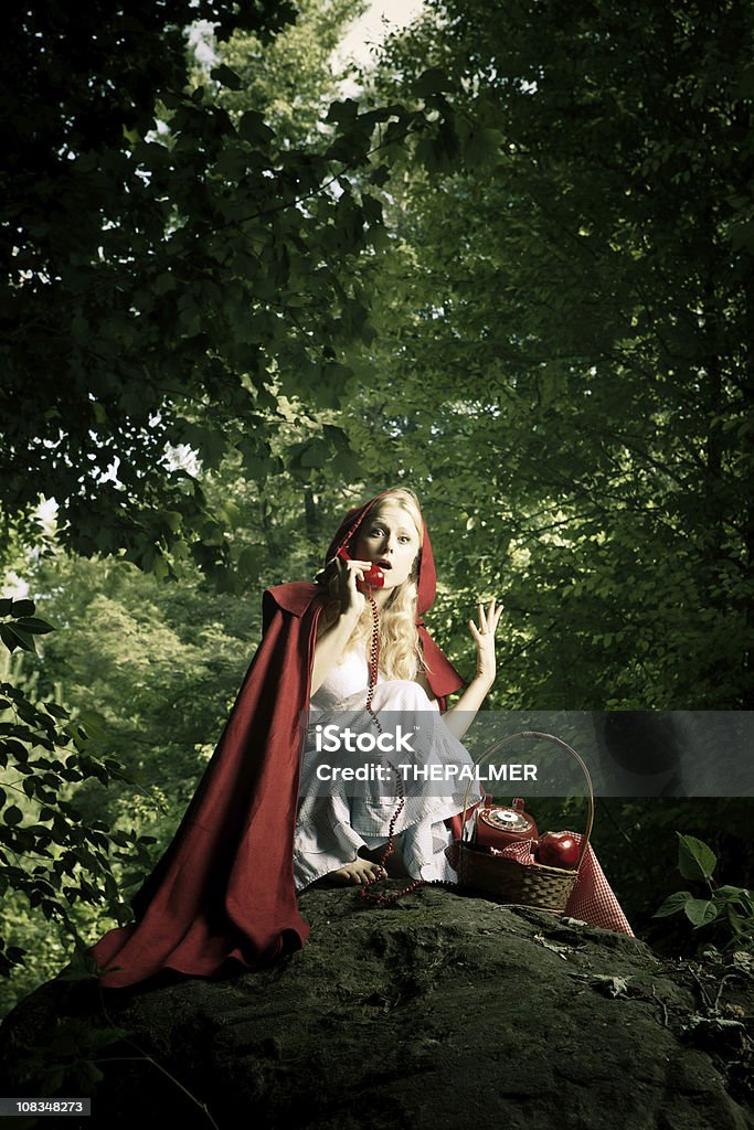 Little Red Riding Hood on the phone grown up Little Red Riding Hood lost in the forest, using her "portable" vintage phone to talk to grandma about the perils of her trip thru the woods Humor Stock Photo
