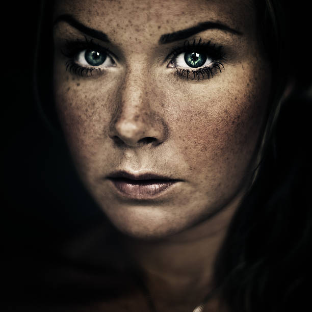 Serious woman Serious woman with lots of freckles woman alone dark shadow stock pictures, royalty-free photos & images