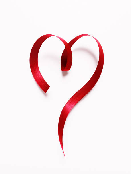 красная лента формирование формы с�ердца на белом фоне - день святого валентина концепция - aids awareness ribbon фотографии стоковые фото и изображения