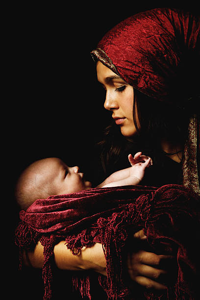 virgin Mary baby Jesus Christ born Christmas Young teen girl embracing holding male infant baby child portraying the Madonna the virgin Mary and baby Jesus Christ at Christmas nativity scene photos stock pictures, royalty-free photos & images