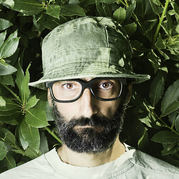 made by TempuraslightbulbOne nerdish looking middle age man looking scared. He is inside some bushes with a lizard on his shoulder. Wearing a green camp hat and black rimmed glasses.