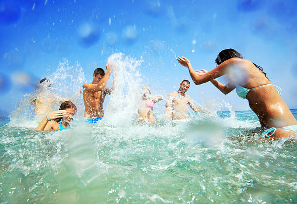 Young people in water spraying each other. Fun in the water - spraying of young people to each other. waist deep in water stock pictures, royalty-free photos & images