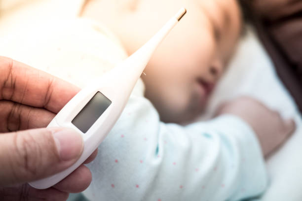 istock mother hand hold thermometer with blurred baby background. 1083487740