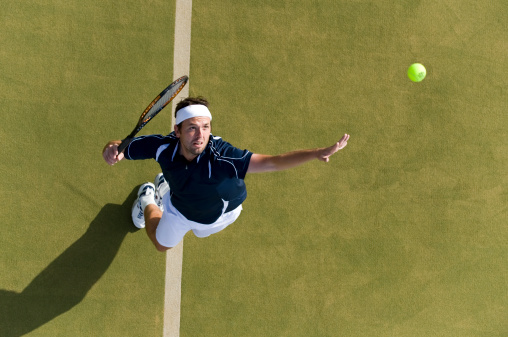 Top view of a professional female tennis player serves the tennis ball on the court with precision and power.