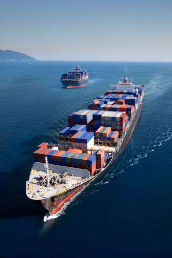 Panoramic back view of a cargo ship carrying containers for import and export, business logistic and transportation in open sea with copy space