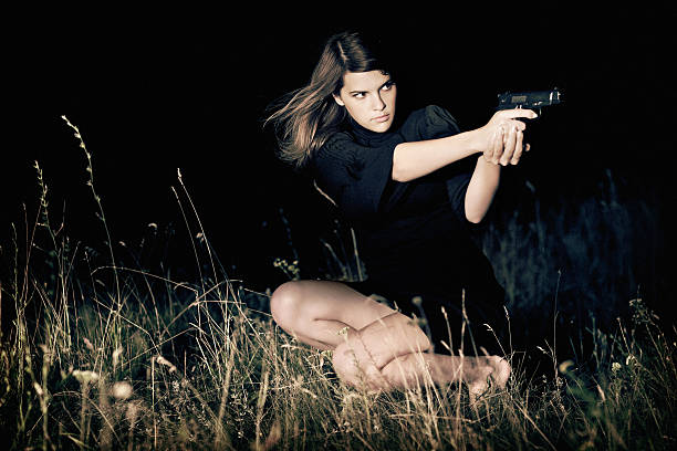 closeup spy woman wear red dress holding black gandgun at the grey background