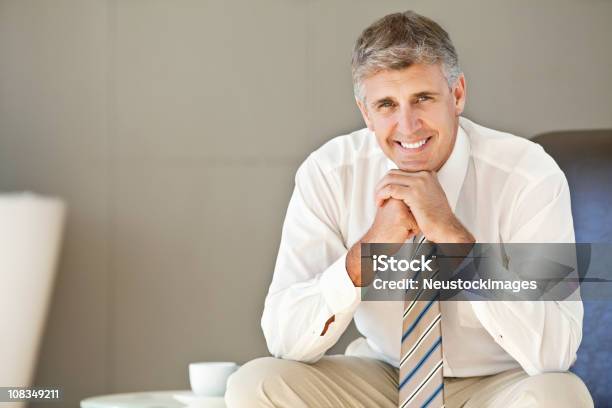 Middleaged Businessman Sitting Confidently Stock Photo - Download Image Now - 40-49 Years, Adult, Adults Only