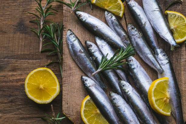 fresh frozen sardines with lemon and rosemary on old, dark, wooden table - prepared fish fish grilled close up imagens e fotografias de stock