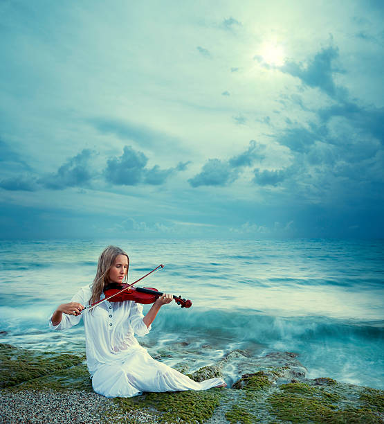 Violinist Female violinist is performing at the beach Long Time Exposure stock pictures, royalty-free photos & images