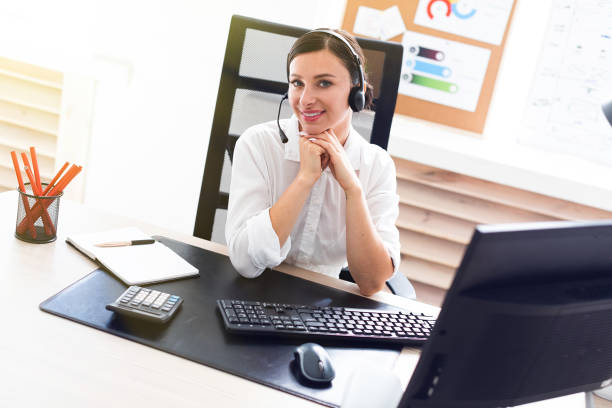 istock A young girl in headphones with a microphone sitting at a computer table. 1083495810