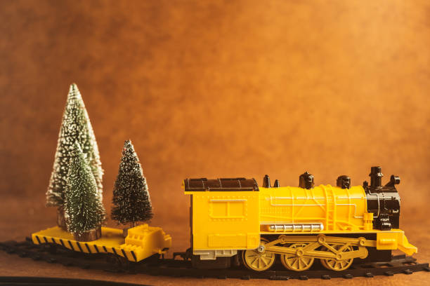 istock christmas eve ideas concept with yellow train is loading big christmas tree with brwon leather background and free copyspace for your ideas text 1083498282